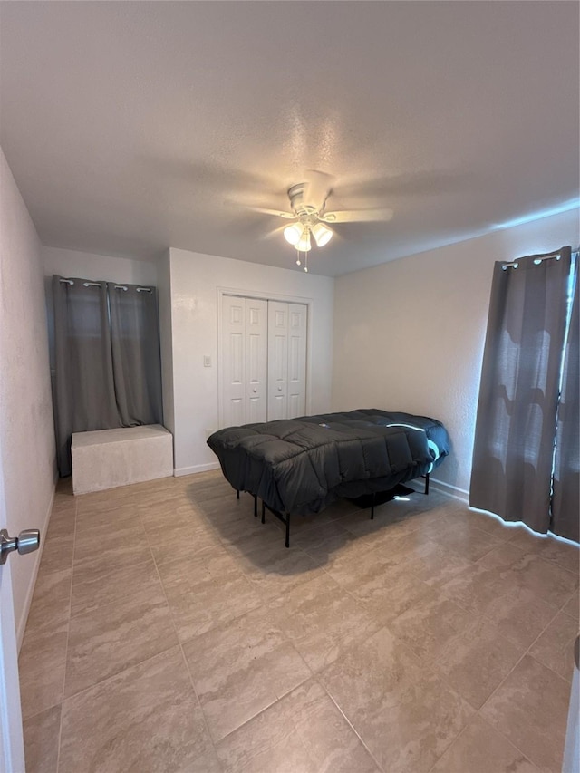 bedroom with a closet, ceiling fan, and baseboards