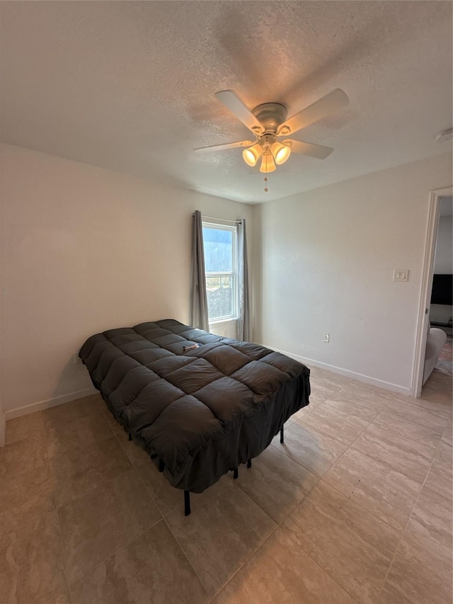 bedroom featuring a textured ceiling, ceiling fan, and baseboards