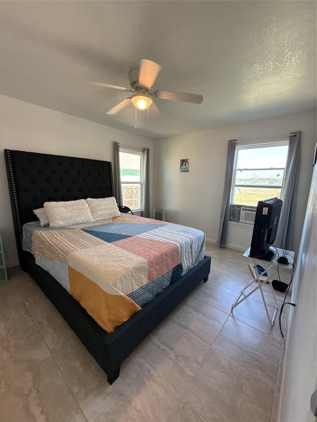 bedroom with baseboards, multiple windows, a ceiling fan, and radiator