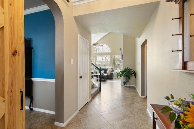 corridor with arched walkways, vaulted ceiling, baseboards, and stairs