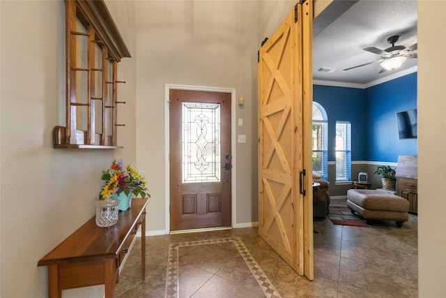 tiled entryway with crown molding, baseboards, a barn door, and plenty of natural light