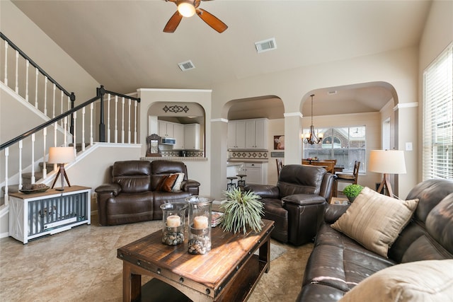 living area with visible vents, ceiling fan with notable chandelier, stairs, and arched walkways