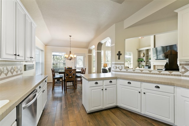 kitchen with stainless steel dishwasher, white cabinets, arched walkways, dark wood-style flooring, and a notable chandelier