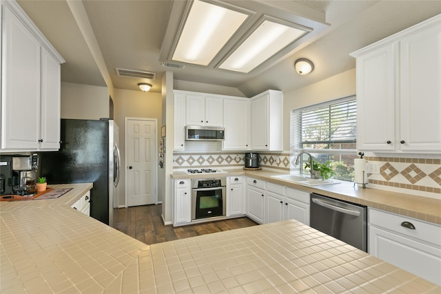 kitchen with decorative backsplash, a sink, visible vents, stainless steel appliances, and dark wood finished floors