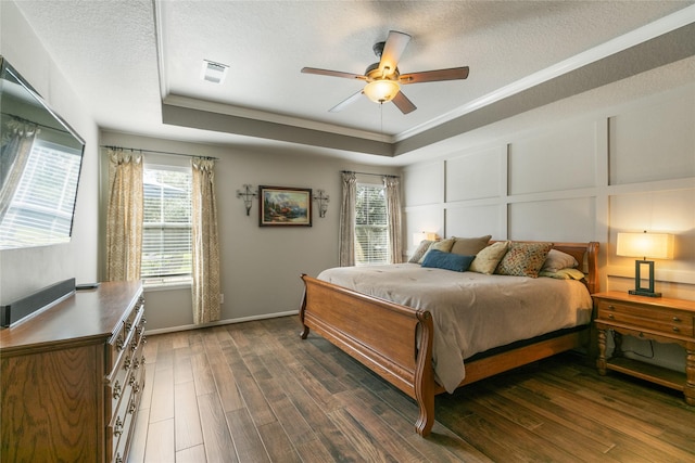bedroom with visible vents, multiple windows, wood finished floors, and a tray ceiling