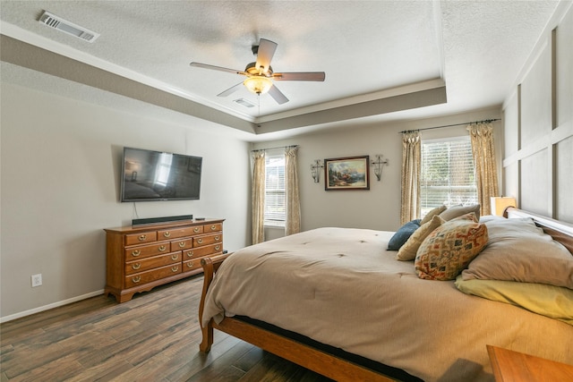 bedroom featuring visible vents, a textured ceiling, dark wood-style flooring, and a tray ceiling