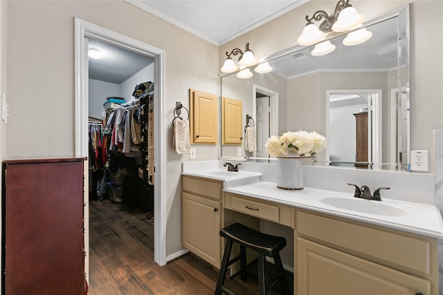 full bathroom featuring a sink, double vanity, a walk in closet, ornamental molding, and wood finished floors