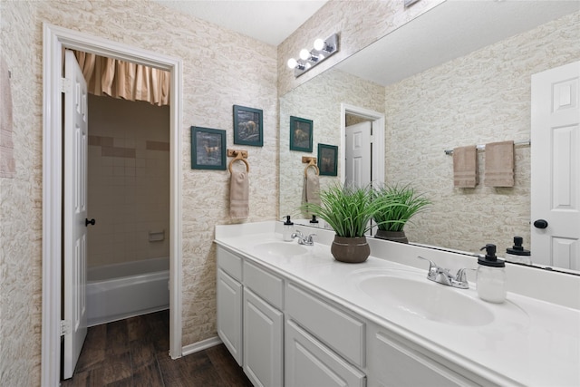 full bath featuring a textured ceiling, double vanity, wood finished floors, and a sink