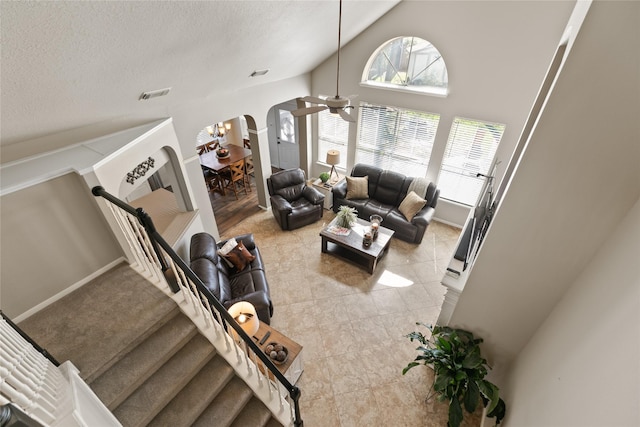 living room featuring arched walkways, visible vents, ceiling fan, a textured ceiling, and high vaulted ceiling