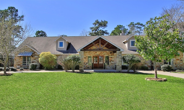 view of front of home featuring a front yard, stone siding, and french doors