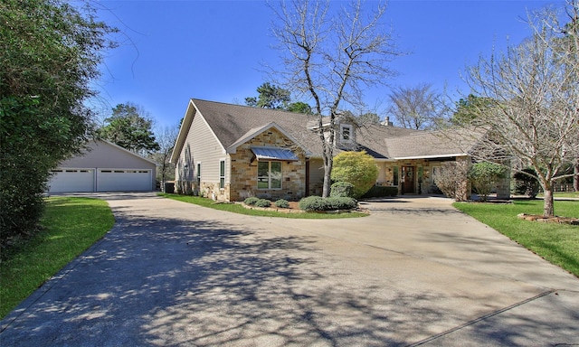 view of front facade with an outbuilding, a detached garage, stone siding, a standing seam roof, and a front yard