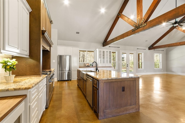 kitchen featuring a sink, white cabinets, open floor plan, appliances with stainless steel finishes, and tasteful backsplash