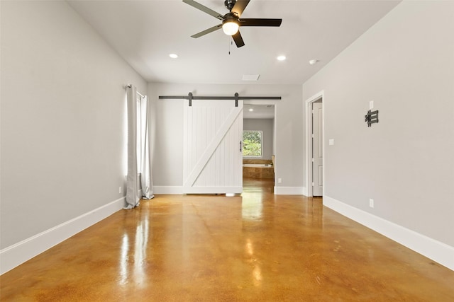 spare room featuring finished concrete flooring, a barn door, baseboards, and recessed lighting