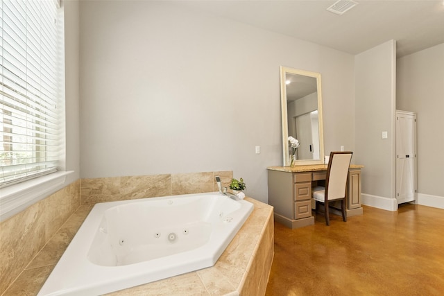 bathroom with visible vents, baseboards, a tub with jets, finished concrete floors, and vanity