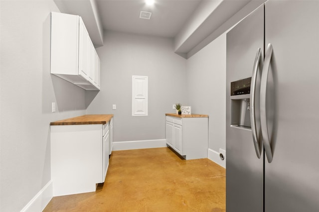 kitchen with visible vents, butcher block countertops, concrete flooring, white cabinetry, and stainless steel refrigerator with ice dispenser