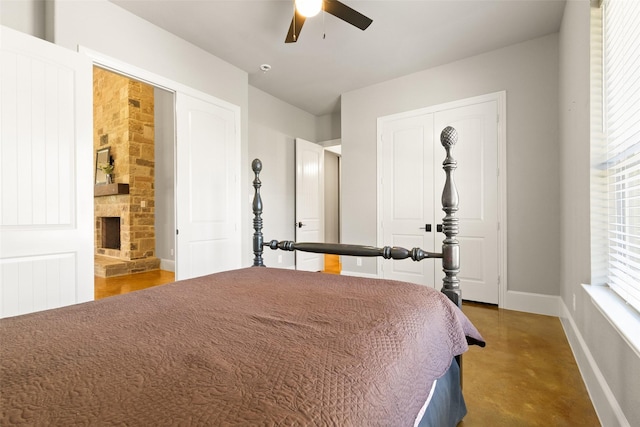 bedroom featuring ceiling fan, a fireplace, baseboards, a closet, and finished concrete floors