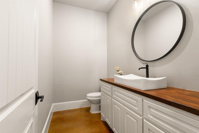 half bathroom featuring baseboards, vanity, and toilet