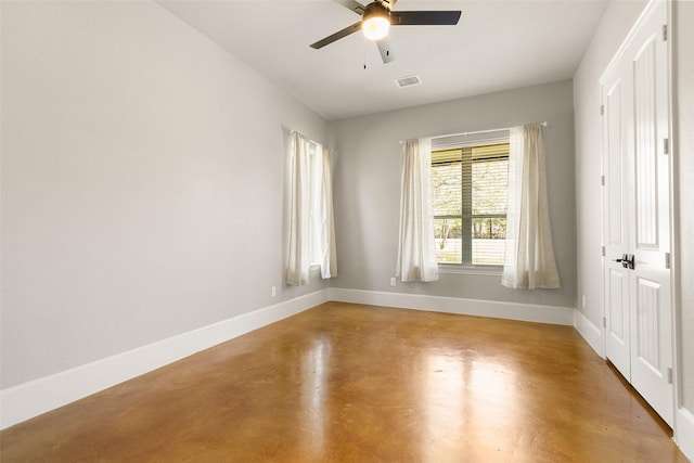 spare room featuring concrete flooring, visible vents, ceiling fan, and baseboards