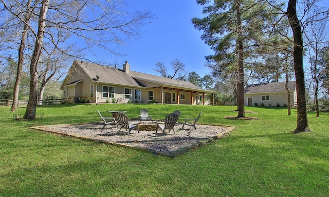 rear view of property with a chimney, a fire pit, fence, and a yard