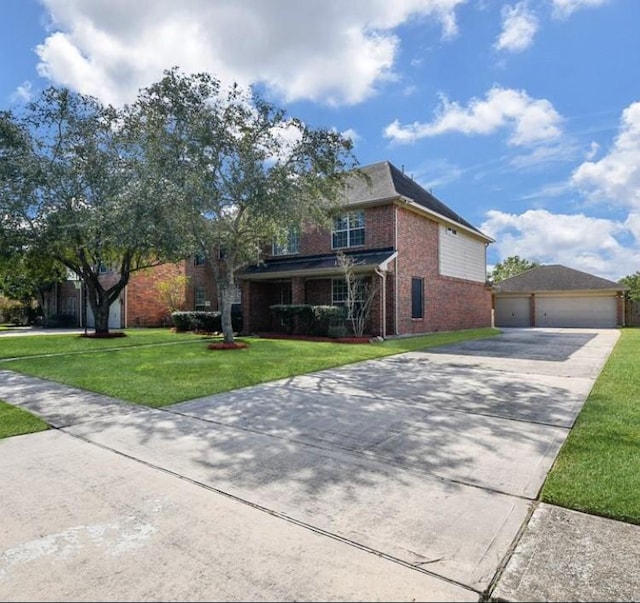 traditional-style home featuring a front yard, an outbuilding, driveway, a garage, and brick siding