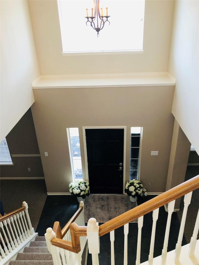 foyer entrance featuring a chandelier, stairs, a high ceiling, and carpet floors