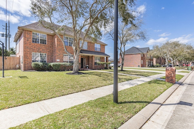 view of front of home with brick siding, a front lawn, and fence