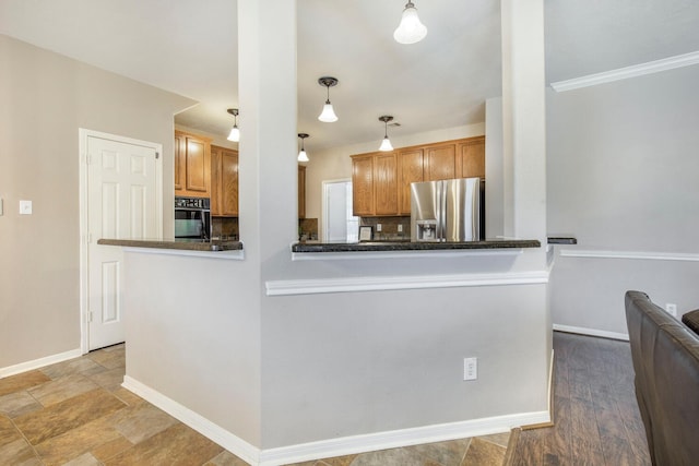 kitchen with oven, tasteful backsplash, dark countertops, stainless steel fridge, and baseboards