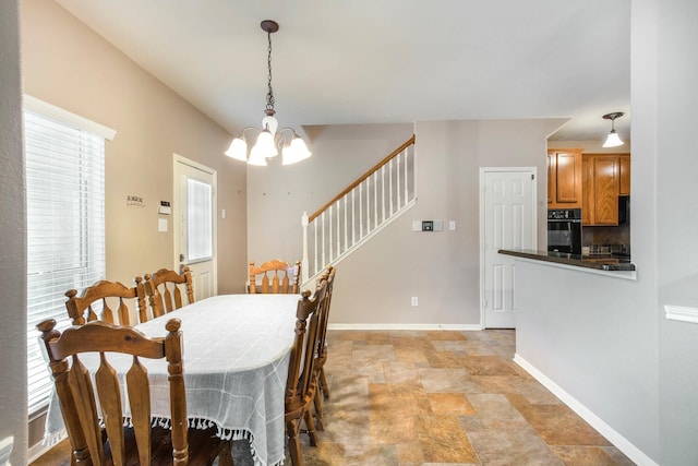 dining room with stone finish floor, baseboards, stairs, and an inviting chandelier