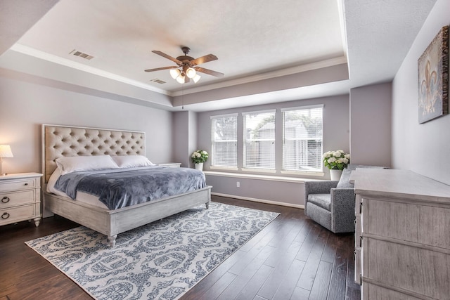 bedroom featuring a tray ceiling, crown molding, visible vents, and dark wood-type flooring