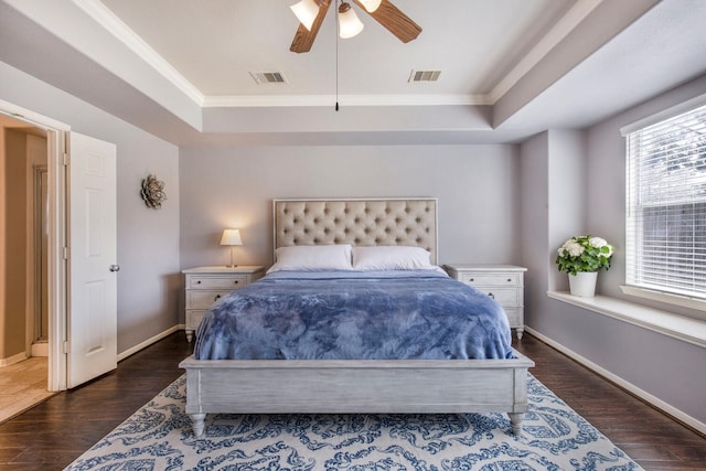 bedroom with a tray ceiling, visible vents, and dark wood-type flooring