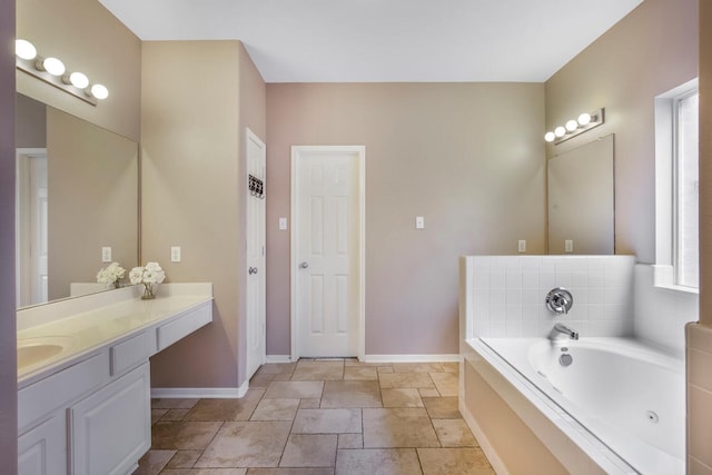 bathroom with vanity, a tub with jets, and baseboards