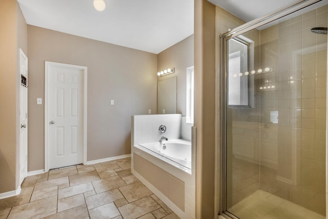 full bathroom with baseboards, a garden tub, and a stall shower