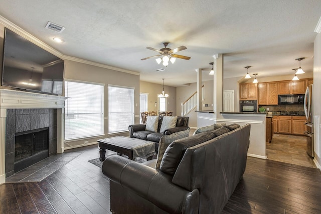 living area with visible vents, ceiling fan, dark wood finished floors, a tile fireplace, and a textured ceiling