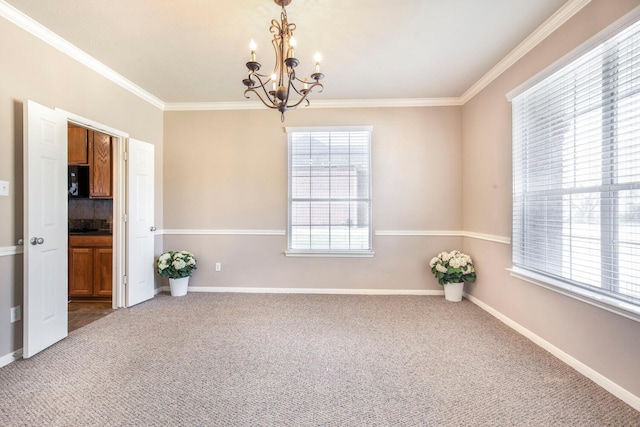 spare room featuring a wealth of natural light, carpet floors, an inviting chandelier, and crown molding