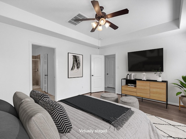 bedroom with baseboards, visible vents, a raised ceiling, ceiling fan, and dark wood-type flooring