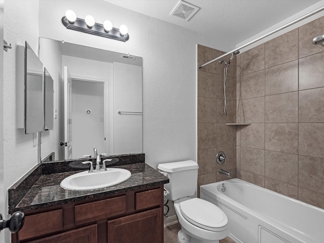 bathroom featuring a textured wall, toilet, vanity, visible vents, and washtub / shower combination