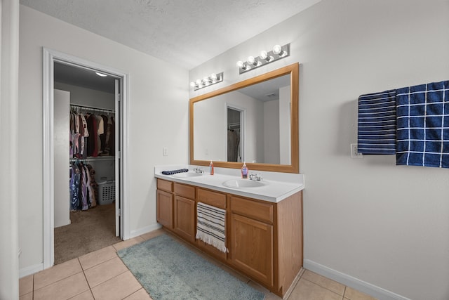 full bathroom with double vanity, a sink, a spacious closet, and tile patterned floors