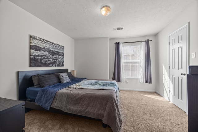 carpeted bedroom featuring a textured ceiling, visible vents, and baseboards