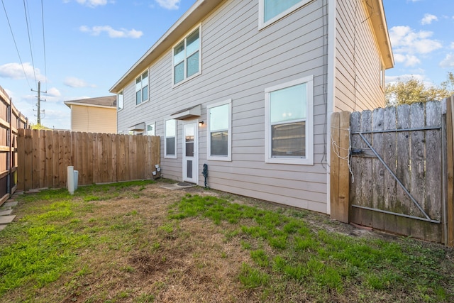 rear view of property featuring a fenced backyard and a lawn