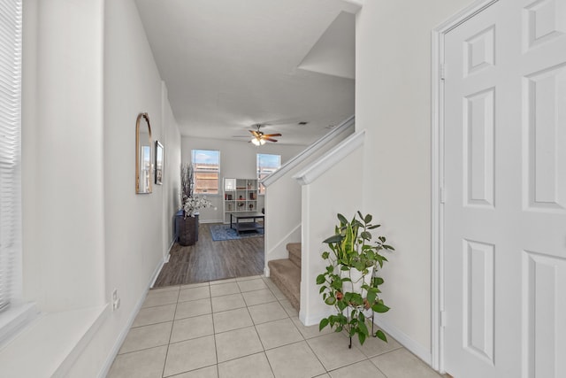 hallway with light tile patterned floors, baseboards, and stairway