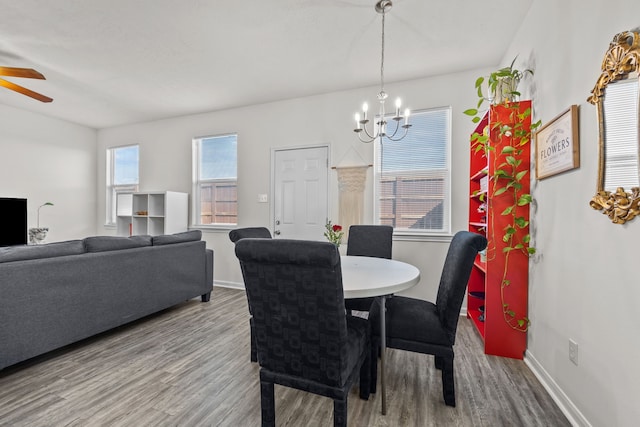 dining area featuring ceiling fan with notable chandelier, wood finished floors, and baseboards