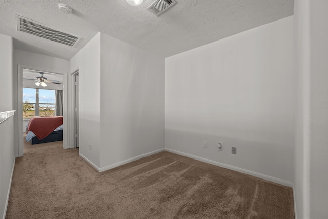 spare room featuring baseboards, carpet, visible vents, and a textured ceiling