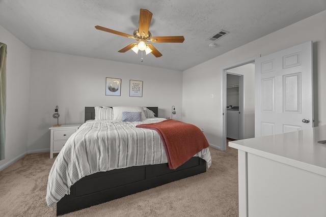 bedroom featuring a textured ceiling, ceiling fan, visible vents, and light colored carpet