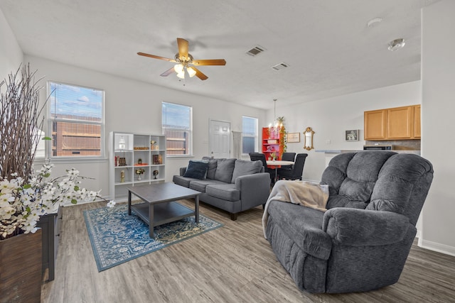 living area with baseboards, wood finished floors, visible vents, and a ceiling fan