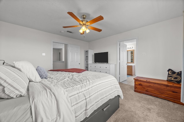 bedroom with light carpet, visible vents, connected bathroom, and a ceiling fan