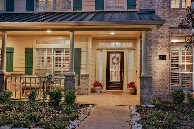 entrance to property with metal roof, brick siding, and a standing seam roof