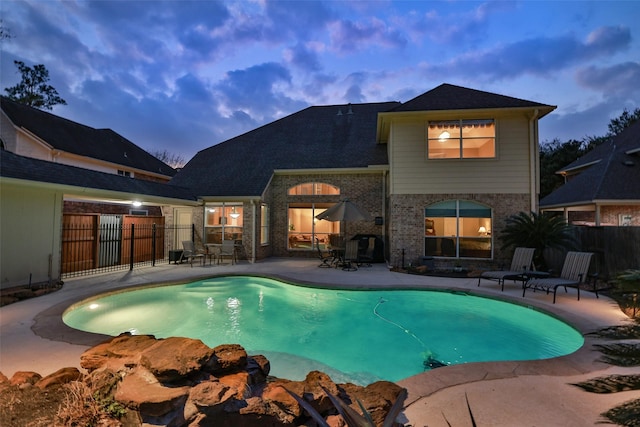 pool at dusk with a fenced in pool, a patio, and fence