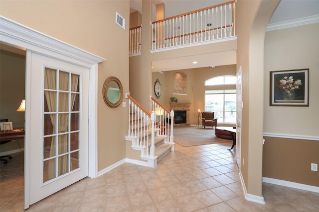 entryway featuring a towering ceiling, baseboards, visible vents, and a glass covered fireplace