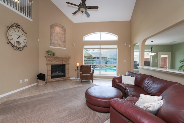 carpeted living room with a ceiling fan, a glass covered fireplace, high vaulted ceiling, baseboards, and tile patterned floors