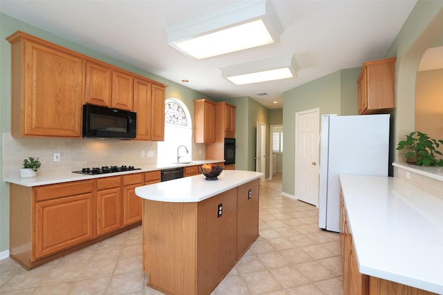 kitchen with a center island, light countertops, decorative backsplash, a sink, and black appliances